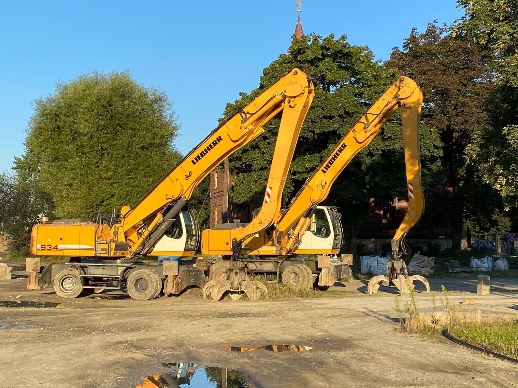 Park maszynowy Przeładunki Wójcik: koparki przeładunkowe Liebherr na placu o zachodzie słońca